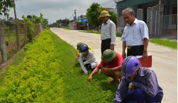 Đồng chí Nguyễn Xuân Oanh (đứng bên phải) cùng Trưởng thôn Hoa Tân tuyên truyền người dân xây dựng khu dân cư kiểu mẫu